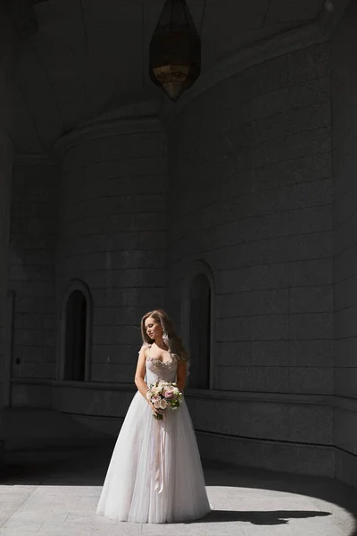古典的なウェディングドレスのスタイリッシュな若い花嫁は、屋外でブライダル花束でポーズを取ります。豪華なウェディングドレスの女性モデル — ストック写真