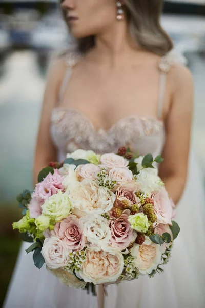 Schöne Braut in einem luxuriösen Brautkleid mit Brautstrauß, mit Pfingstrosen und Rosen Blumen — Stockfoto