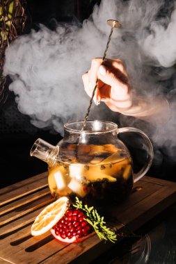 Koyu arkaplanda meyve çayı olan cam çaydanlık. sıcak çayın buharı