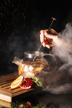 Koyu arkaplanda meyve çayı olan cam çaydanlık. sıcak çayın buharı