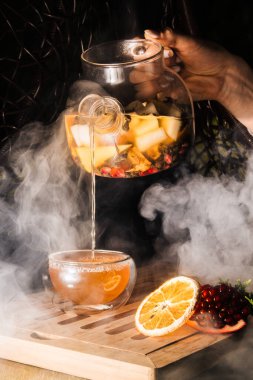 Koyu arkaplanda meyve çayı olan cam çaydanlık. sıcak çayın buharı