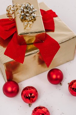 Noel eşyaları altın kutu kırmızı kurdele beyaz arka planda büyük yay ve toplar