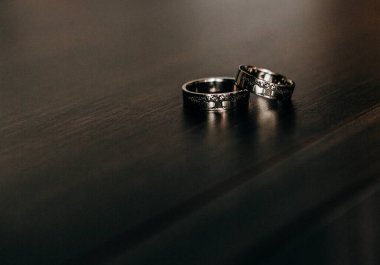 Tahta arka planda altın alyanslar ve parlak mücevherler.