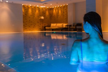 Kız havuza geri döndü. Güzel arka ışık ve mavi berrak su.