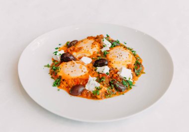 Çırpılmış yumurta, zeytinli yumurta ve beyaz tabakta peynir.