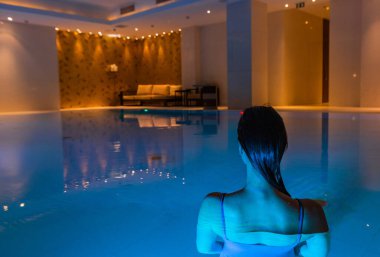 Kız havuza geri döndü. Güzel arka ışık ve mavi berrak su.