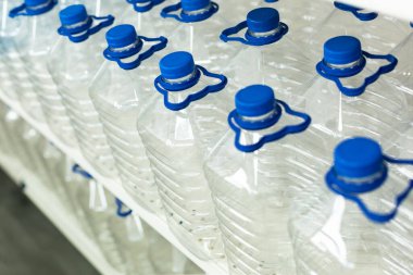 Su için bir sürü şişe kapaklı ve saplı vitrinde bir sırada duruyor.