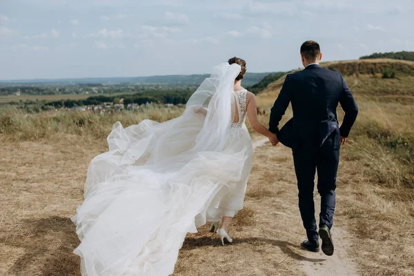 couple in love wedding together outside field path landscape sky veil wind freedom