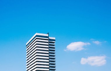 Bir gökdelen beyaz bina gökyüzünde yükseliyor. Bulutlar inşa ediliyor.