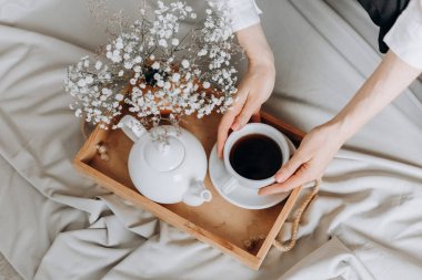 Sabah istirahat eden kadın elinde çay ve çiçeklerle hafta içi dinleniyor.