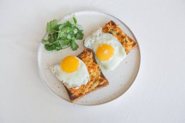 Yağda yumurtalı ekmek, erimiş peynir ve beyaz tabakta kişniş.