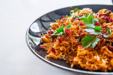 Maydanoz, nar ve nar tohumlarıyla süslenmiş bir tabakta karidesli risotto.