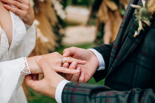 穿着格子呢西装的新郎把戒指戴在新娘的手上 — 图库照片