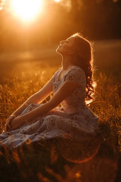 Elbiseli Bir Kadın Gün Batımında Çayırda Oturuyor Güneşin Arka Işınları — Stok fotoğraf