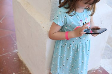 Kırmızı bilezik oteli olan çocuk akıllı telefon dokunuşu kullanıyor.