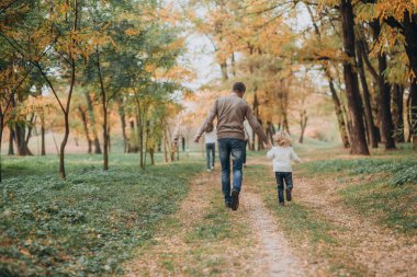 Sonbahar parkında mutlu bir aile hafta sonu. Ağaçlar sararmış.