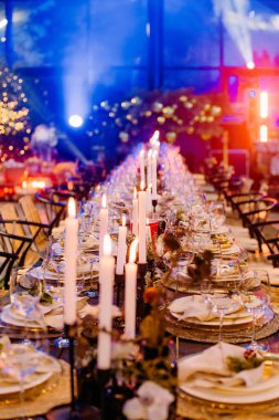 Noel simgeleriyle süslenmiş şenlikli büyük bir masa. Mumlar parıldıyor.
