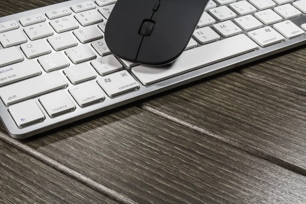 Notepad, keyboard, mouse and cellphone on wood table