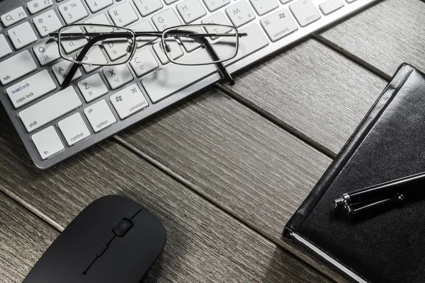 Kladblok, toetsenbord, muis en cellphone op houten tafel — Stockfoto