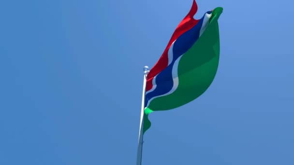 ガンビアの国旗が青い空に向かって風に乗って飛んでいます — ストック動画