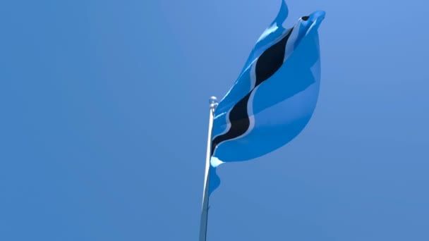Botswanas flagga flyger i vinden mot en blå himmel. — Stockvideo