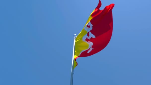 De nationale vlag van Bhutan wappert in de wind tegen een blauwe lucht — Stockvideo