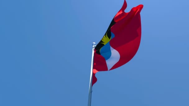 A bandeira nacional de Antígua Barbuda está voando no vento contra um céu azul — Vídeo de Stock