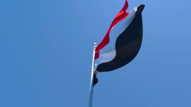 Yemen 'in ulusal bayrağı mavi gökyüzüne karşı rüzgarda dalgalanıyor.