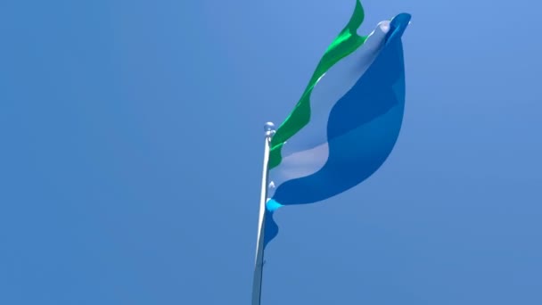 La bandera nacional de Sierra Leona ondea en el viento contra un cielo azul — Vídeos de Stock