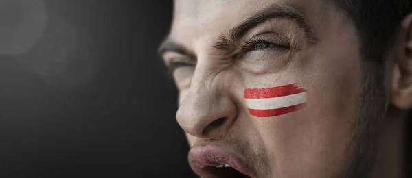 A screaming man with the image of the countrys national flag on his face — Stock Photo, Image