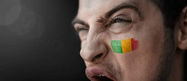 Um homem gritando com a imagem da bandeira nacional do Mali em seu rosto — Fotografia de Stock