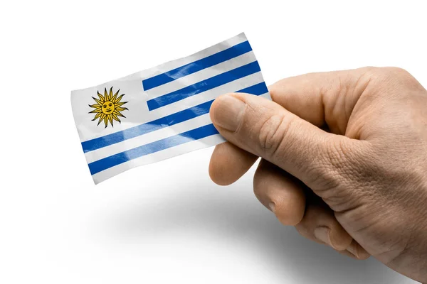 Mano sosteniendo una tarjeta con bandera nacional el Uruguay — Foto de Stock