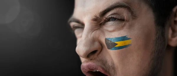 Un hombre gritando con la imagen de la bandera nacional de Bahamas en su rostro —  Fotos de Stock