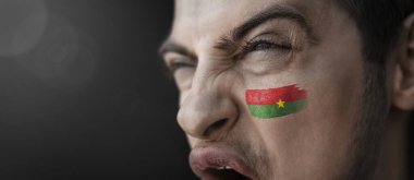 Yüzünde Burkina Faso bayrağı resmi olan çığlık atan bir adam.