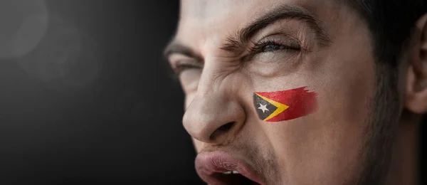 Un hombre gritando con la imagen de la bandera nacional de Timor Oriental en su rostro —  Fotos de Stock