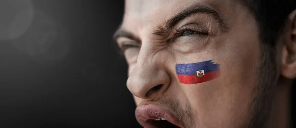 En skrikande man med bilden av Haitis flagga i ansiktet — Stockfoto