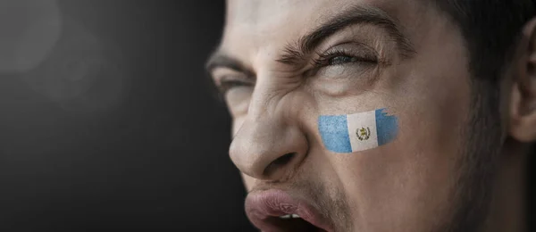 Um homem gritando com a imagem da bandeira nacional da Guatemala em seu rosto — Fotografia de Stock