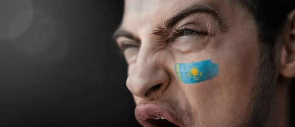 En skrikande man med bilden av Kazakstans nationalflagga i ansiktet. — Stockfoto