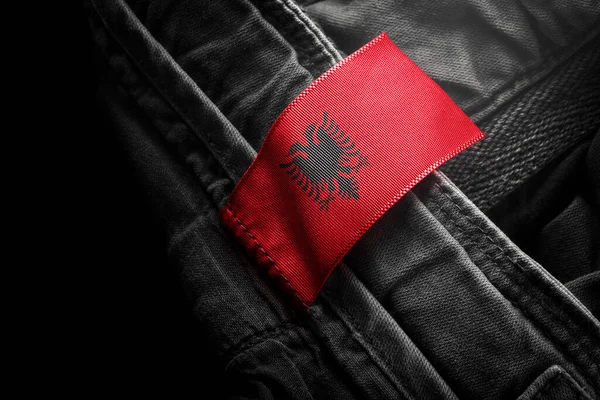 Značka na tmavém oblečení v podobě vlajky Albánie — Stock fotografie