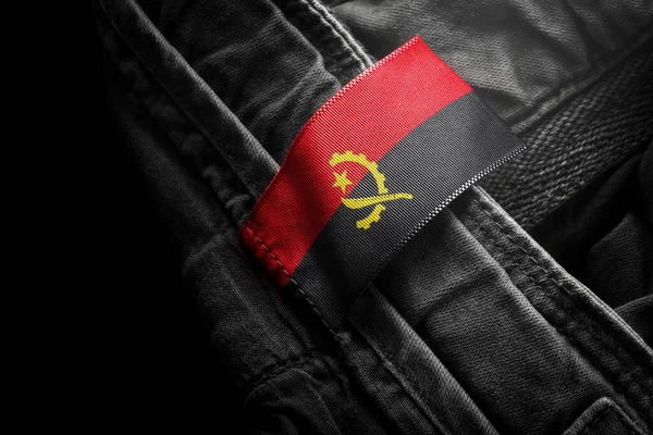 Etiqueta en la ropa oscura en forma de la bandera de Angola — Foto de Stock