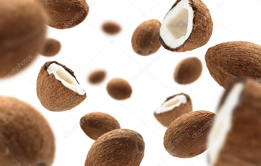 Whole and half cocoanuts levitate on a white background
