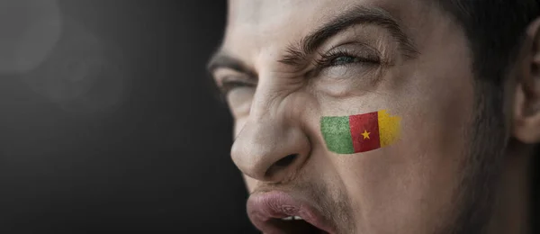 Křičící muž s vyobrazením Kamerunské národní vlajky na tváři — Stock fotografie