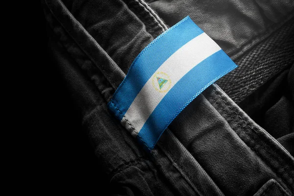 Etichetă pe haine întunecate sub forma steagului Nicaragua — Fotografie, imagine de stoc