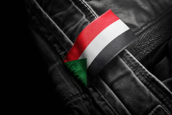 Etiqueta en la ropa oscura en forma de la bandera de Sudán —  Fotos de Stock