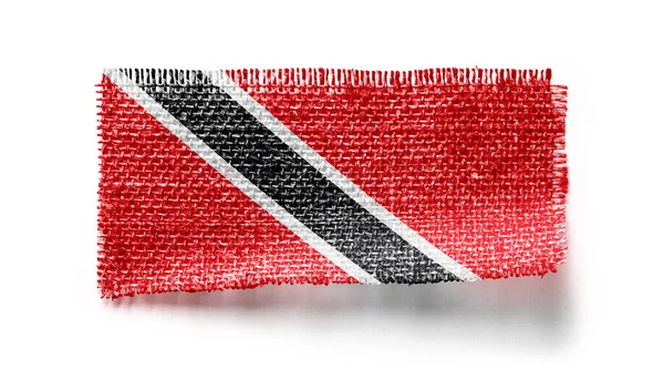 Flagge von Trinidad und Tobago auf einem Stück Stoff auf weißem Hintergrund — Stockfoto