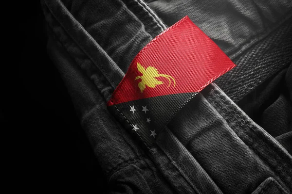 Etiqueta en la ropa oscura en forma de la bandera de Papúa Nueva Guinea —  Fotos de Stock