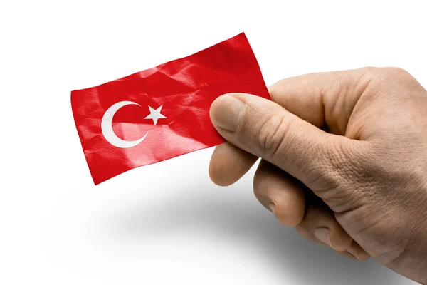 Mano sosteniendo una tarjeta con una bandera nacional la Turquía — Foto de Stock