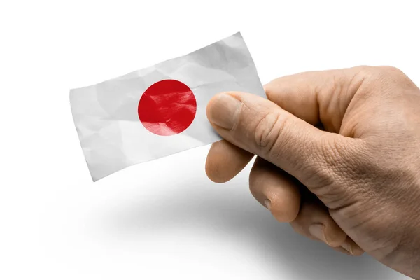 Mão segurando um cartão com uma bandeira nacional o Japão — Fotografia de Stock