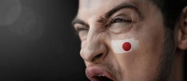 Ένας άντρας που ουρλιάζει με την εικόνα της Ιαπωνικής σημαίας στο πρόσωπό του. — Φωτογραφία Αρχείου