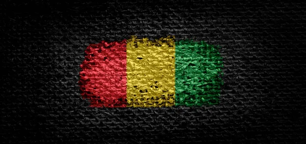 Bandera nacional de Guinea sobre tela oscura — Foto de Stock